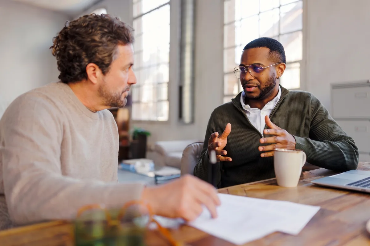 A man listening closely as a colleague makes her case across a table